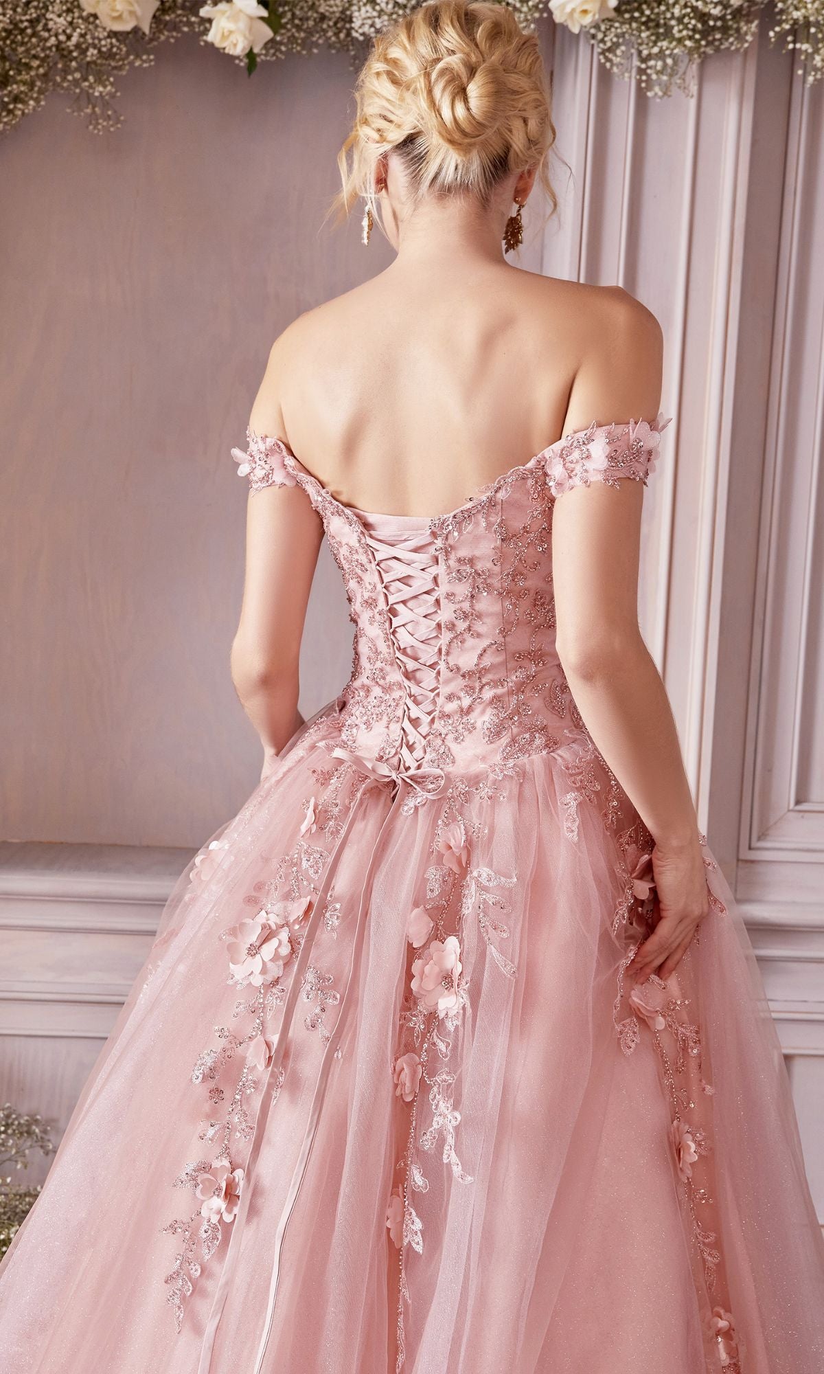 A woman wearing the Off-Shoulder Long Sweetheart Prom Ball Gown CD0185 with pink floral-lace appliques and a lace-up back stands facing away in an elegant setting.